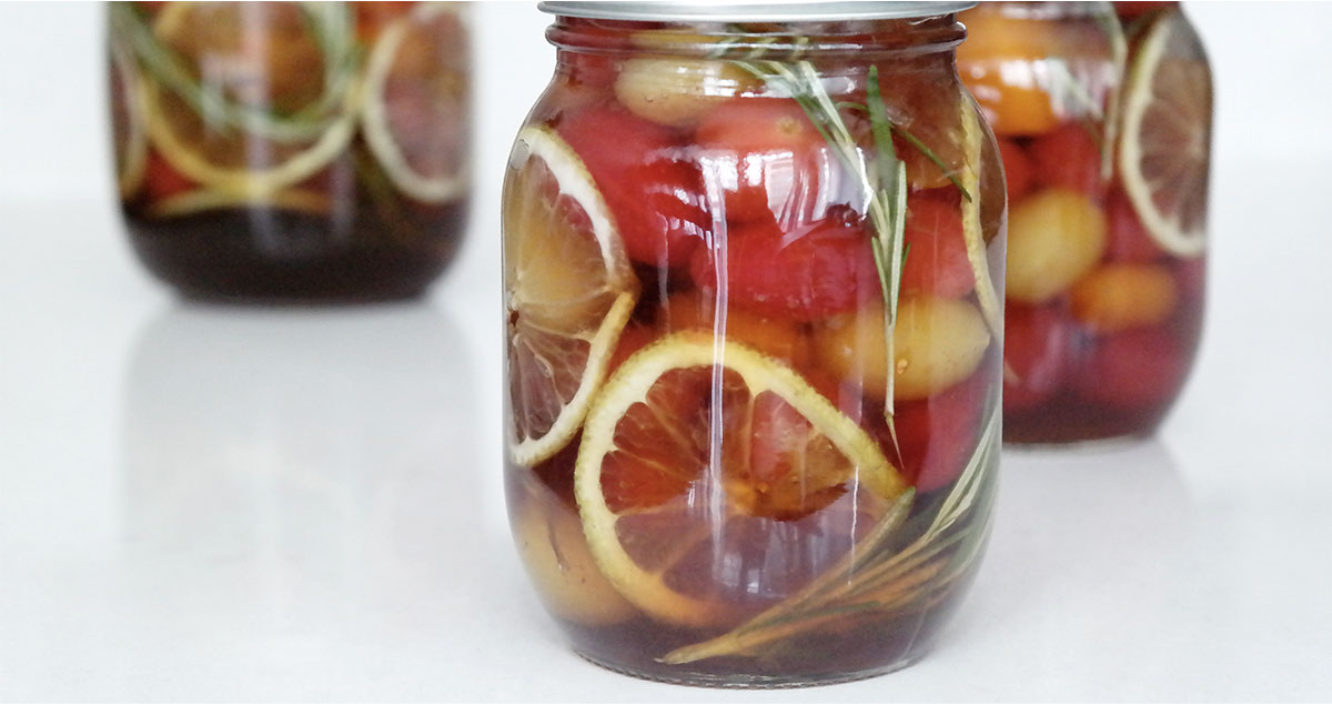 tomato preserves in a glass jar with yuzu extract, plum extract, rosemary, and lemon slices